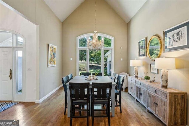 dining space featuring an inviting chandelier, light hardwood / wood-style floors, and high vaulted ceiling