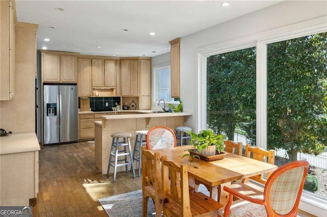 kitchen with kitchen peninsula, stainless steel fridge with ice dispenser, dark wood-type flooring, and light brown cabinetry