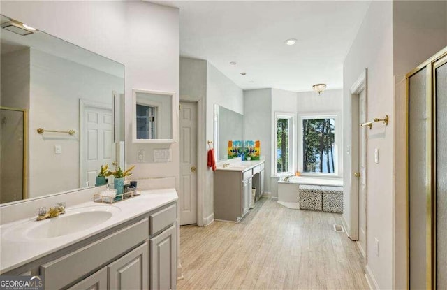 bathroom with hardwood / wood-style floors, vanity, and shower with separate bathtub