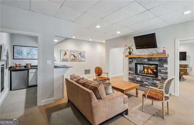 carpeted living room featuring a paneled ceiling, a stone fireplace, and pool table