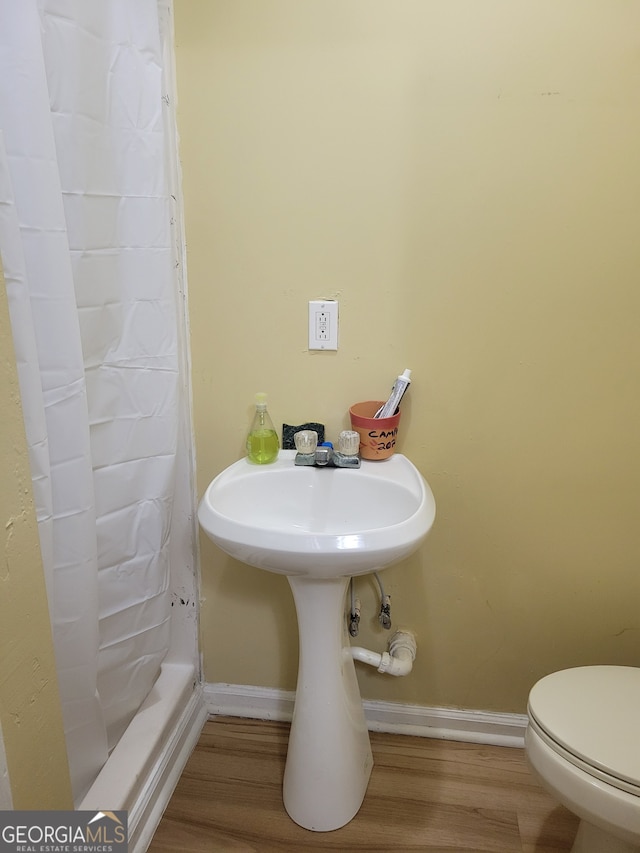 bathroom featuring toilet, wood-type flooring, and a shower with shower curtain