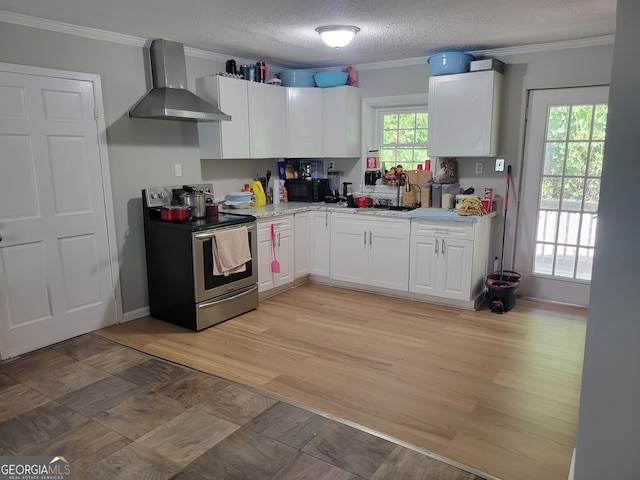 kitchen with electric range, white cabinetry, light wood-type flooring, crown molding, and wall chimney exhaust hood