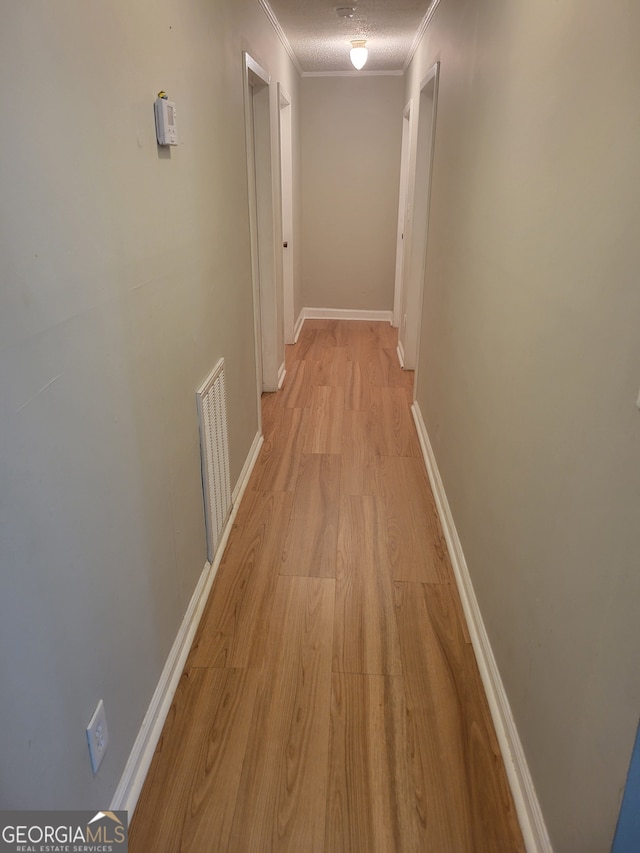 corridor with light hardwood / wood-style floors, crown molding, and a textured ceiling