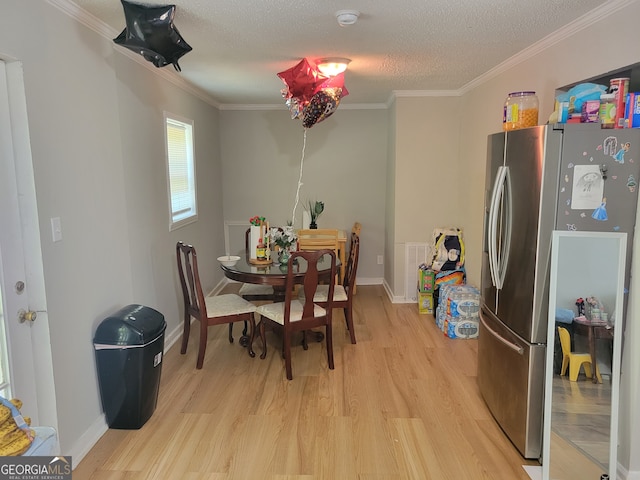 dining space with light hardwood / wood-style floors, ornamental molding, and a textured ceiling