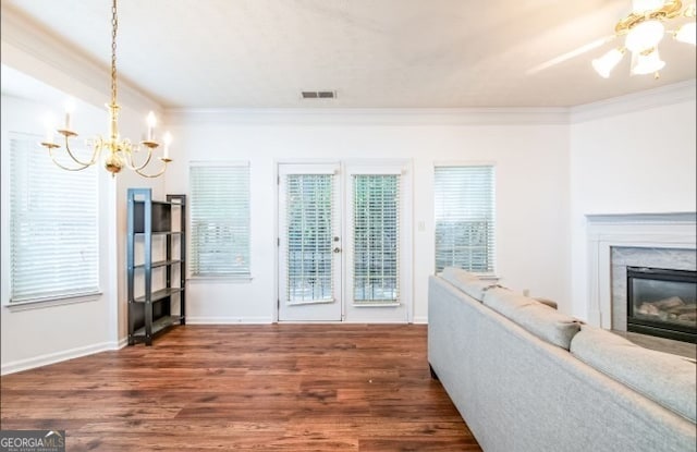 unfurnished living room featuring crown molding, a notable chandelier, a fireplace, and dark hardwood / wood-style flooring