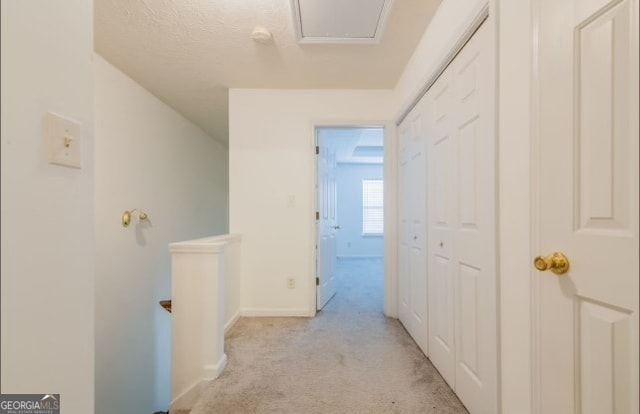 hall featuring a textured ceiling and light colored carpet