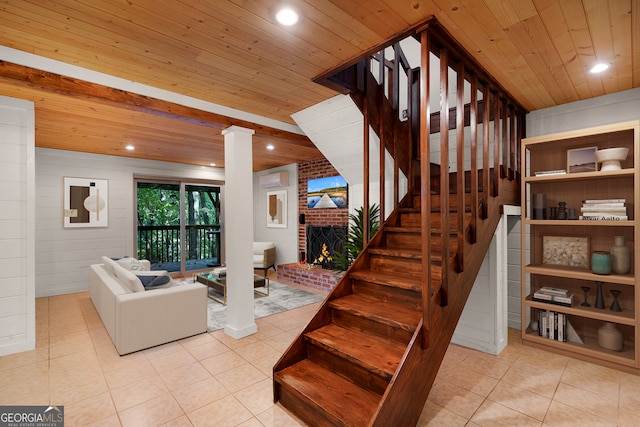 stairs with a brick fireplace, tile patterned floors, and wooden ceiling