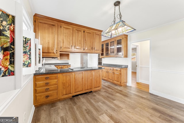 kitchen featuring hanging light fixtures, kitchen peninsula, sink, crown molding, and light wood-type flooring