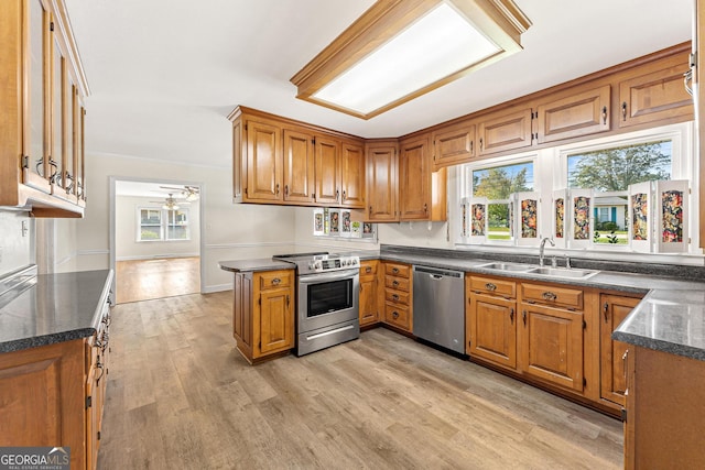 kitchen with kitchen peninsula, sink, light wood-type flooring, appliances with stainless steel finishes, and ceiling fan