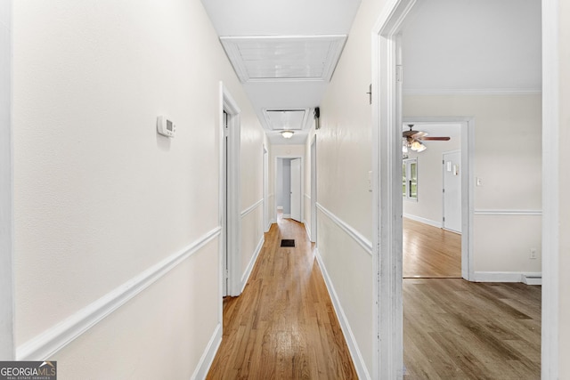 hall with ornamental molding and light wood-type flooring