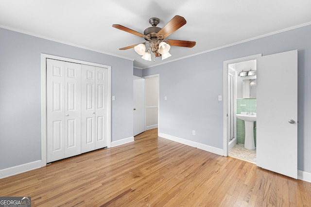 unfurnished bedroom featuring light hardwood / wood-style floors, a closet, ensuite bath, and ceiling fan