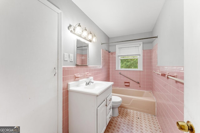 full bathroom with vanity, toilet, tiled shower / bath combo, and tile walls