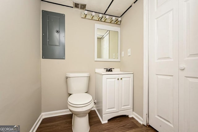 bathroom with vanity, toilet, hardwood / wood-style flooring, and electric panel