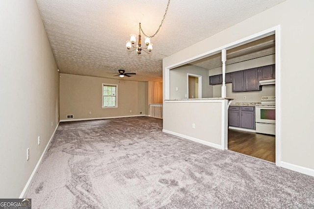 unfurnished living room with dark colored carpet, a textured ceiling, and ceiling fan with notable chandelier