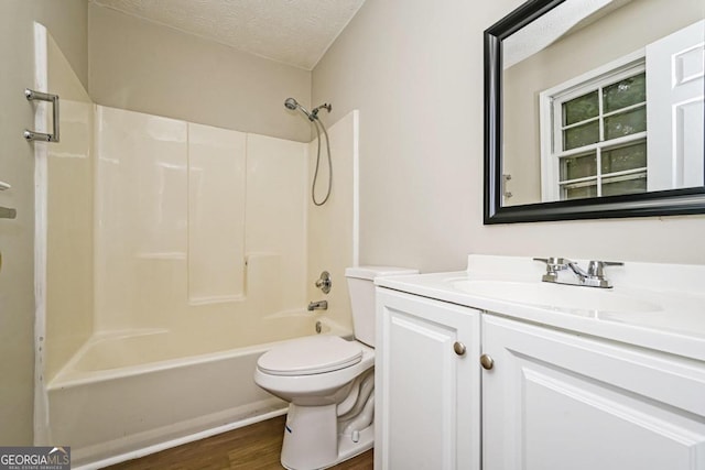 full bathroom featuring toilet, wood-type flooring,  shower combination, vanity, and a textured ceiling