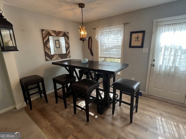 dining room with a textured ceiling, a chandelier, and wood-type flooring