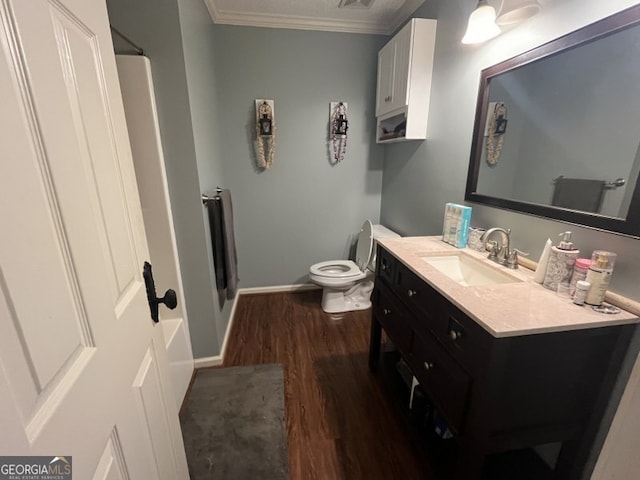 bathroom featuring vanity, hardwood / wood-style floors, ornamental molding, and toilet