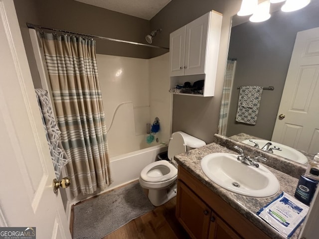 full bathroom with a textured ceiling, hardwood / wood-style floors, toilet, shower / bath combo with shower curtain, and vanity