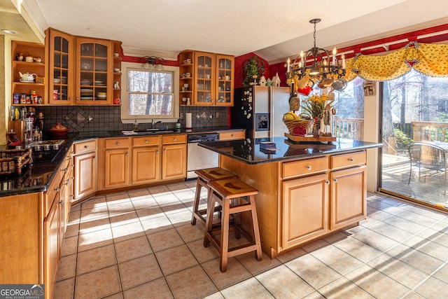 kitchen featuring sink, dishwasher, an inviting chandelier, dark stone countertops, and pendant lighting