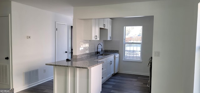 kitchen featuring backsplash, stone counters, white cabinets, sink, and dark hardwood / wood-style floors