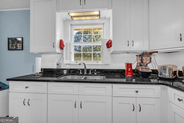 kitchen with sink, white cabinets, dark stone counters, and tasteful backsplash