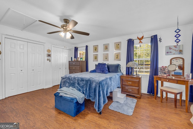 bedroom featuring ceiling fan, wood-type flooring, ornamental molding, and two closets