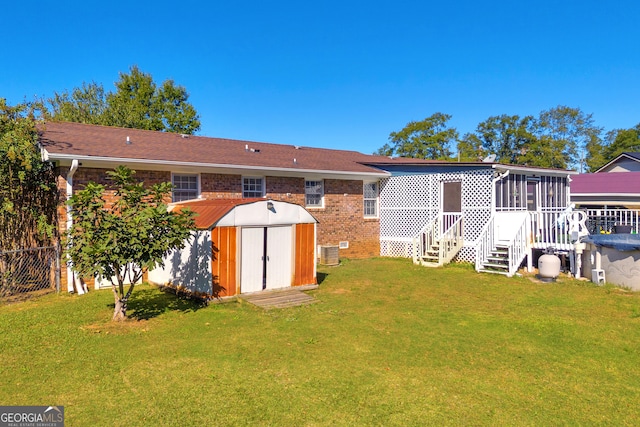 back of property featuring central air condition unit, a storage shed, a yard, and a sunroom