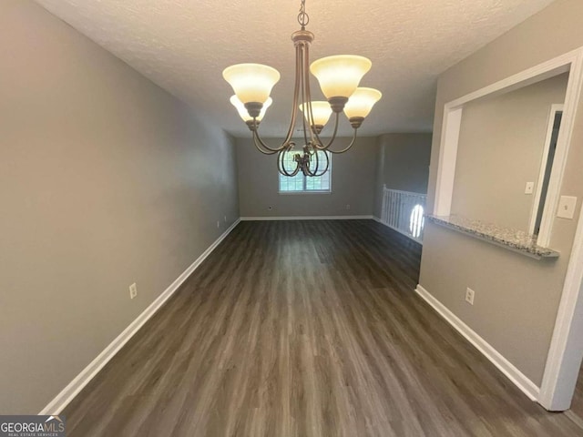 unfurnished dining area featuring a textured ceiling, dark hardwood / wood-style floors, and an inviting chandelier