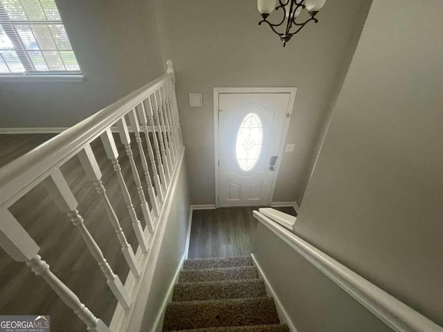 stairs with hardwood / wood-style floors and an inviting chandelier