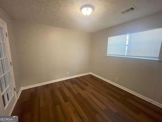 empty room featuring dark wood-type flooring and a textured ceiling