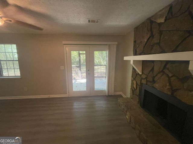 living room with ceiling fan, a textured ceiling, dark wood-type flooring, a fireplace, and french doors