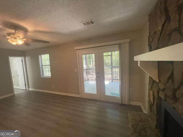 doorway featuring dark wood-type flooring, a stone fireplace, a textured ceiling, and french doors