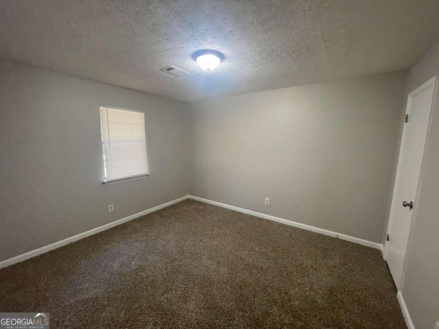 carpeted empty room featuring a textured ceiling