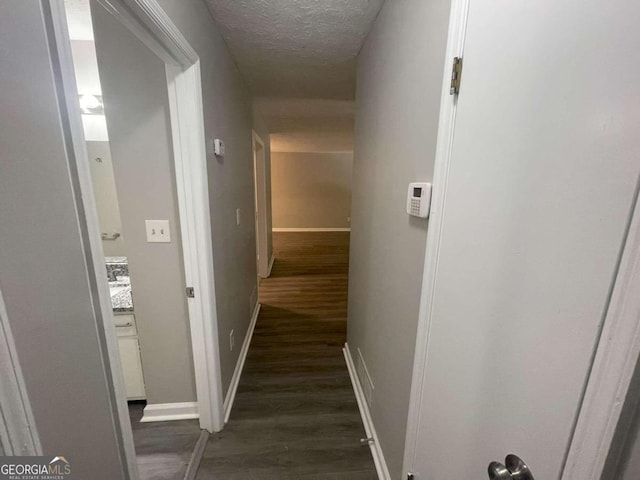 hallway with dark wood-type flooring and a textured ceiling