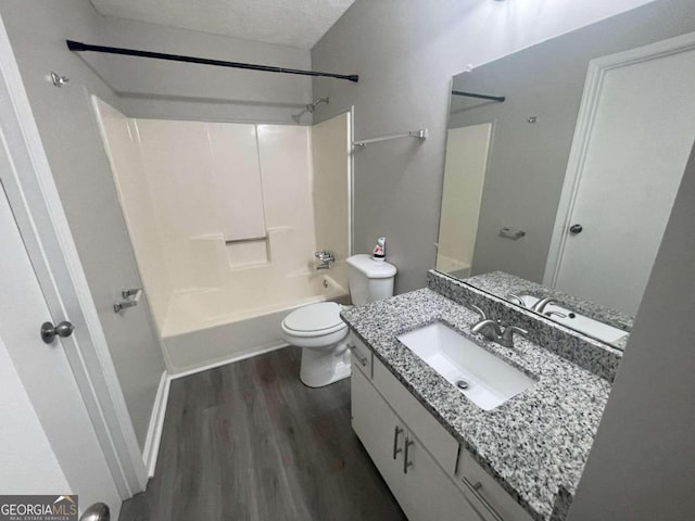 full bathroom featuring shower / washtub combination, hardwood / wood-style floors, a textured ceiling, toilet, and vanity