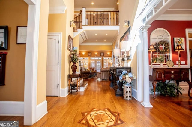 foyer with a towering ceiling, crown molding, and hardwood / wood-style floors