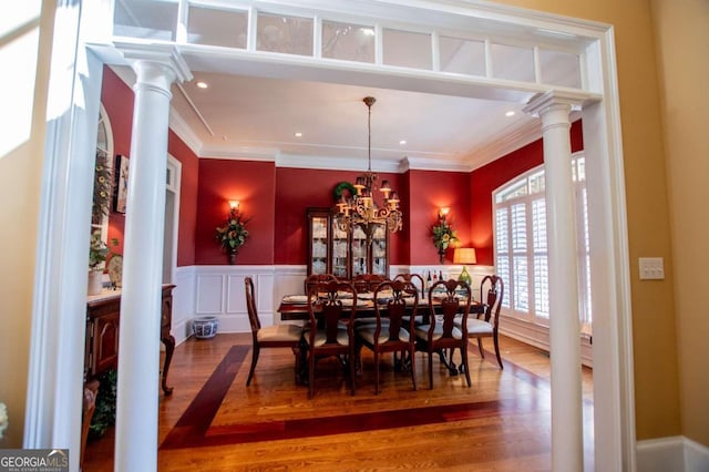 dining space featuring decorative columns, crown molding, an inviting chandelier, and dark hardwood / wood-style flooring