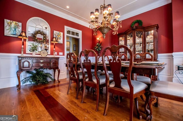 dining space with crown molding, wood-type flooring, and an inviting chandelier