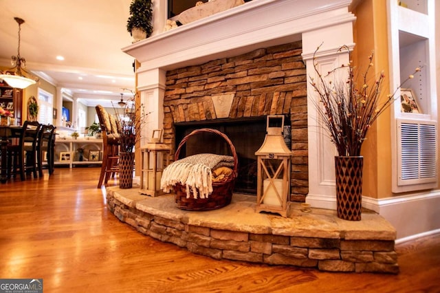 details featuring crown molding, a stone fireplace, and wood-type flooring