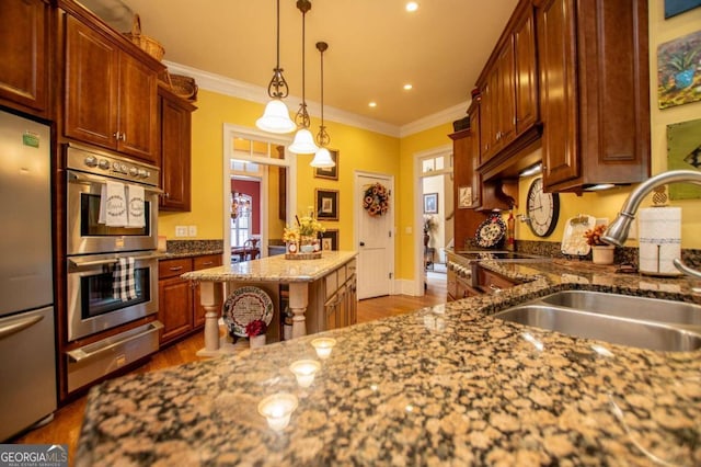 kitchen with appliances with stainless steel finishes, sink, dark stone counters, decorative light fixtures, and crown molding