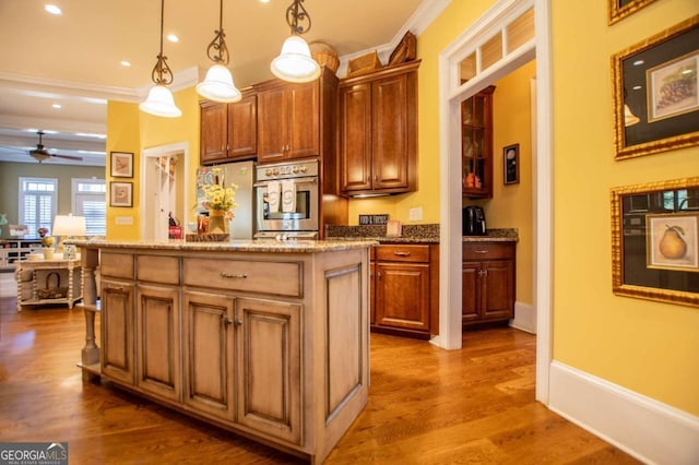 kitchen featuring a kitchen island, dark wood-type flooring, hanging light fixtures, stainless steel appliances, and light stone counters