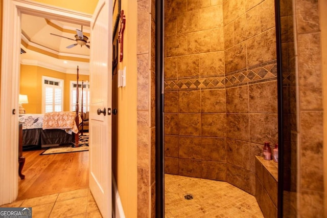 bathroom with a shower with door, hardwood / wood-style flooring, crown molding, a raised ceiling, and ceiling fan