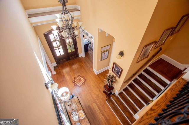 entryway featuring french doors, a notable chandelier, a towering ceiling, and hardwood / wood-style floors