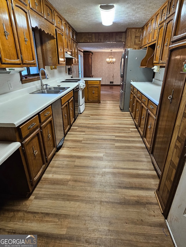 kitchen featuring light hardwood / wood-style flooring, sink, a notable chandelier, white electric stove, and a textured ceiling