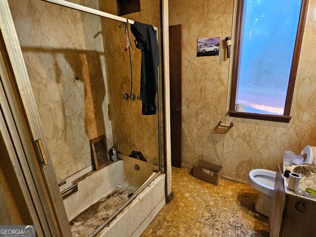 bathroom featuring bath / shower combo with glass door and toilet