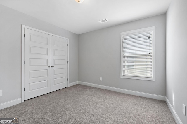 unfurnished bedroom with light carpet and a closet