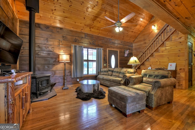 living room with wood-type flooring, wooden walls, and lofted ceiling