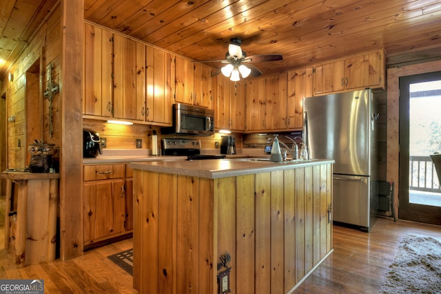 kitchen featuring light wood-type flooring, stainless steel appliances, ceiling fan, wooden ceiling, and wood walls