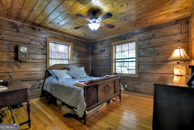 bedroom featuring wooden walls, light hardwood / wood-style flooring, ceiling fan, and wooden ceiling