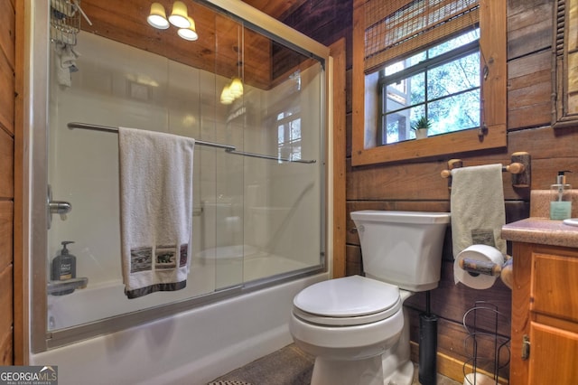 bathroom with toilet, wooden walls, combined bath / shower with glass door, and vanity